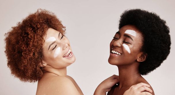Cream, face treatment and girl friends with black women and happiness for skincare and beauty in studio. Wellness, people and spa aesthetic with lotion and moisturizer for facial and cosmetic product. - Foto, Imagen