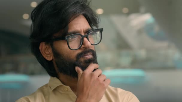Indian pensive man in eyeglasses thinking. Close up thoughtful male face look distance indoors pondering business idea searching problem solution. Arabian businessman in glasses think touching chin - Záběry, video