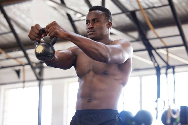 Black man with kettlebell in gym, fitness and power with arm muscle training, bodybuilder and weightlifting exercise. Biceps, strong and bodybuilding, focus and serious with commitment to workout. - Fotoğraf, Görsel
