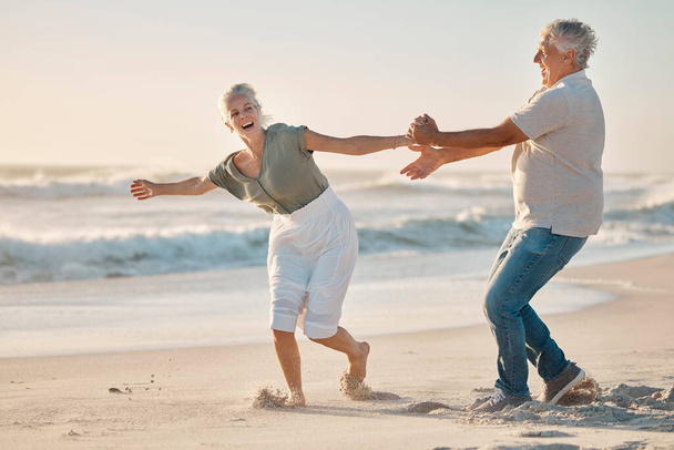 Веселая взрослая пара играет на пляже. Старшая пара веселится на пляже вместе. Счастливая старшая пара, беззаботная на берегу океана вместе. Зрелая пара, соединяющаяся на пляже вместе. - Фото, изображение