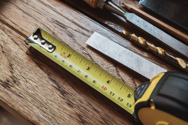 Мера ленты с линейно измеряемыми маркировками на деревянном фоне, DIY maker и концепция деревообработки. селективный фокус - Фото, изображение