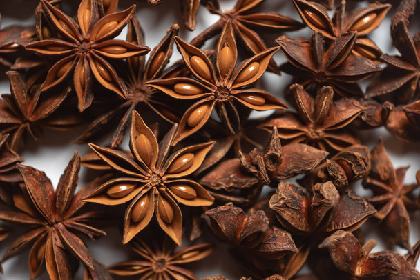 Fragrant spices for preparing drinks and desserts. Food additive in dishes. Brown spices. Spices for making mulled wine. A lot of star anise on a white background close-up - Photo, Image
