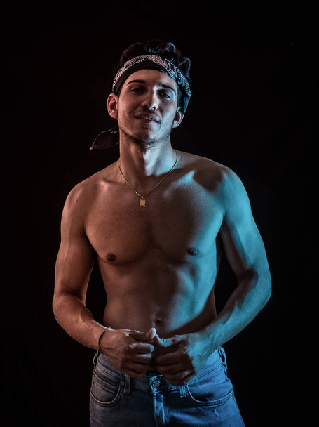 Handsome athletic shirtless young man standing confident, front view, looking at camera in studio on black background - Photo, Image