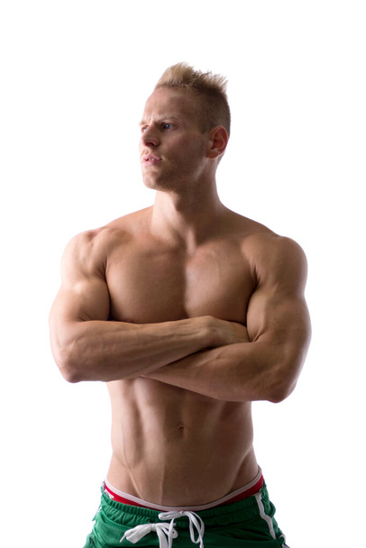 Shirtless muscular young man standing with arms crossed on chest, looking away to a side, isolated on white - Photo, image