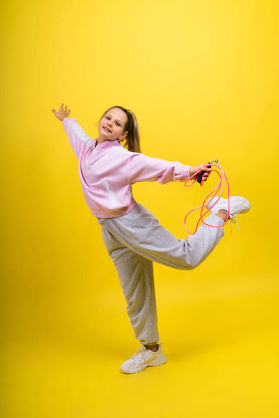 Αξιολάτρευτο θηλυκό παιδί με σχοινάκι να πηδάει σε στούντιο. - Φωτογραφία, εικόνα