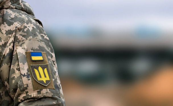 Украинский солдат в армии и флаге, герб с золотым трезубцем на военном фоне. Вооружённые силы Украины. - Фото, изображение