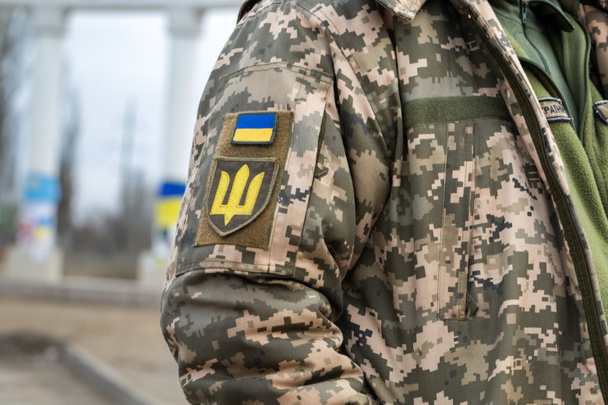 Ukrán katona a hadseregben és a zászlóban, címer arany szigonnyal, katonai egyenruhás háttérrel. Ukrajna fegyveres erői. - Fotó, kép