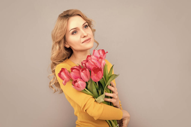 Frau mit floralem Geschenk zum Frauentag auf grauem Hintergrund. - Foto, Bild
