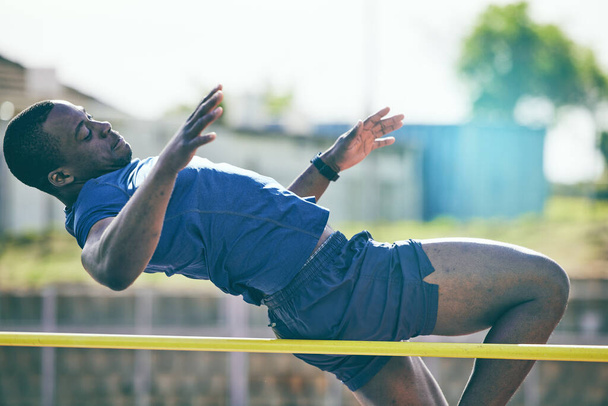 Man, high jump and fitness or athletics at a stadium for training, energy and cardio against sky background. Jumping, athlete and male outdoors for performance, endurance and competition on mock up. - Foto, immagini