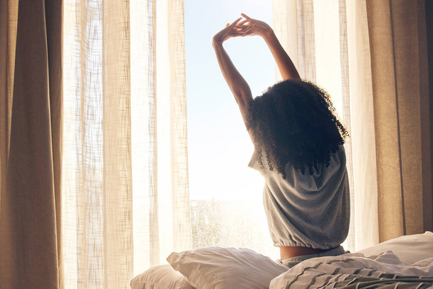 Black woman, back stretching and waking up in home bedroom after sleeping or resting. Relax, peace and comfort of female stretch after feeling fresh, awake and well rested to start morning in bed - 写真・画像
