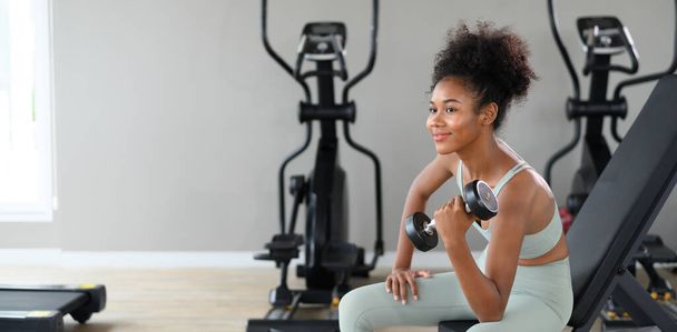 Sporty fitness African American woman working out with dumbbells strength and strength endurance at the gym - Foto, afbeelding