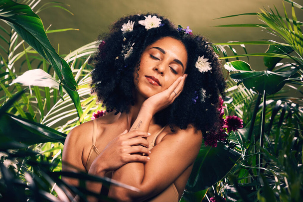 Beauty, flowers and black woman in studio for wellness, skincare and creative advertising in a jungle. Facial, skin and girl model relax in zen, peace and products from nature, forest and aesthetic. - Photo, Image