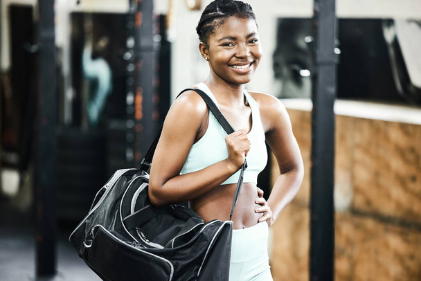 Das Fitnessstudio ist für den Tag fertig. eine attraktive junge Frau, die allein in der Sporthalle steht und eine Sporttasche in der Hand hält - Foto, Bild