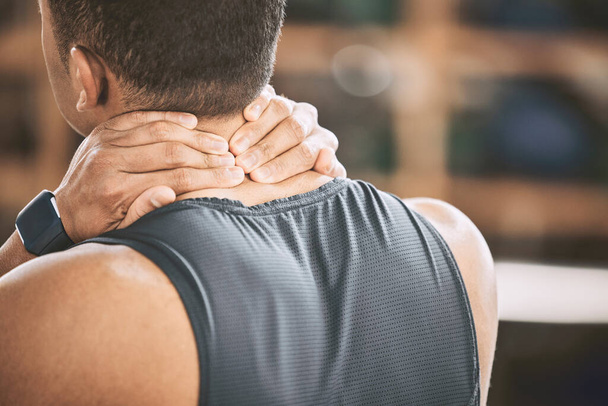 Back of a fit man experiencing pain. Athlete experiencing neck pain in the gym. Muscular trainer with back pain in the gym. Bodybuilder athlete discomfort in his neck during a workout. - Foto, imagen