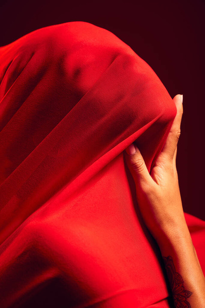 Woman, red fabric and hide face for fashion, aesthetic and sensual with dark studio background. Gen z model, cloth or silk veil for creativity, vision and art with retro, vintage or creative clothes. - Photo, Image