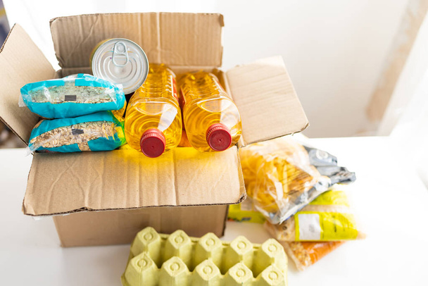 段ボール箱には様々な缶詰、パスタ、シリアルが入っています。寄付や食品配送のコンセプト. - 写真・画像
