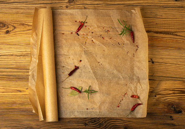 Καφέ χαρτί ψησίματος με βότανα και μπαχαρικά, Kraft φύλλο χαρτιού μαγειρικής σε ξύλινο φόντο υφής, λαδόκολλα φούρνου Mockup, λαδόκολλα - Φωτογραφία, εικόνα