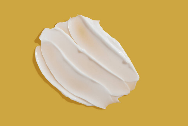 Білий красивий крем змащує плями на жовтому тлі. Текстура косметичного продукту зі шкіри. Крем для обличчя, годинник для лосьйону для тіла
 - Фото, зображення