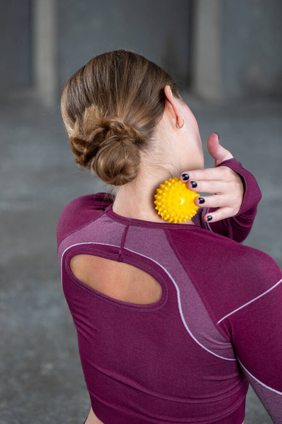 The athlete does a relaxing massage of the neck and back with the help of a prickly rubber ball. The concept of self-massage, physiotherapy. - Foto, immagini