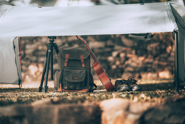 Camping equipment, bags, shoes, ukulele, tripod in tent in the morning. Object camp, Travel and vocation concept. - Foto, Bild