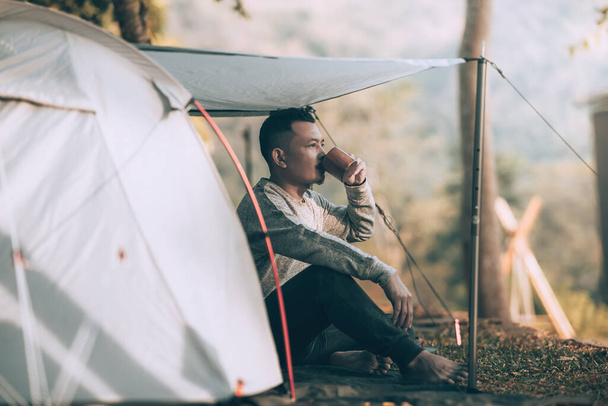 Man playing drink coffee in the morning during a camping trip in the forest on holiday. Vocation and travel concept. - Foto, immagini