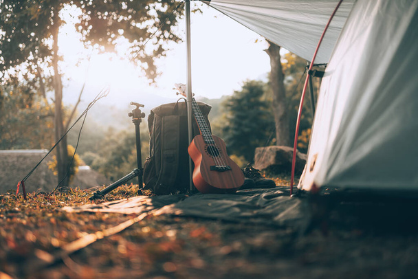 Camping equipment, bags, shoes, ukulele, tripod beside the tent in the morning. Object camp, Travel and vocation concept. - 写真・画像