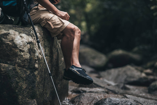 hiker with backpack sitting on the rock in waterfall while a rest. hiking and adventure concept. - Foto, Imagem