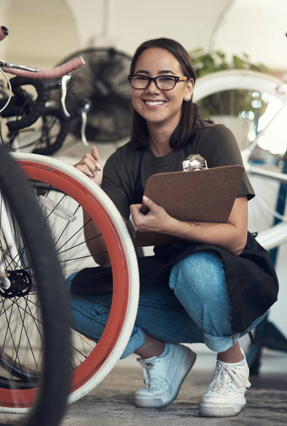 I double-check everything before it leaves the shop. Full length shot of an attractive young woman crouching in her bicycle shop and holding a clipboard - Fotoğraf, Görsel