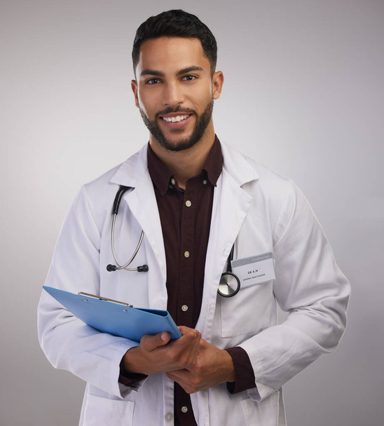 Ive got your results right here. a handsome young doctor standing alone in the studio and holding a clipboard - Foto, Imagen