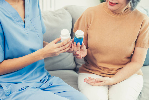 Caregiver advising contented senior woman on medication in the living room. Medication for seniors, nursing house, healthcare at home. - Foto, Bild
