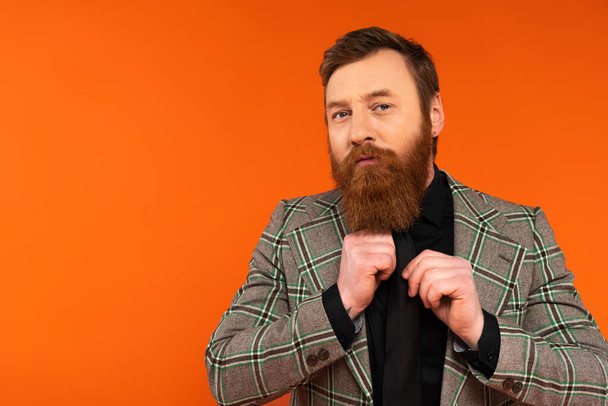 Bearded man in checkered jacket looking at camera isolated on red  - Foto, afbeelding