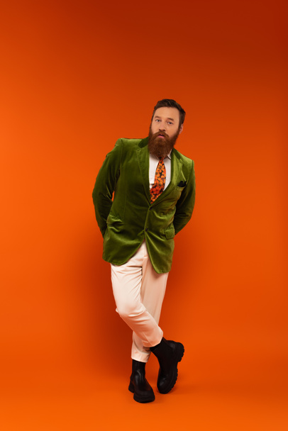 Full length of stylish man in velour jacket posing on red background  - Foto, afbeelding