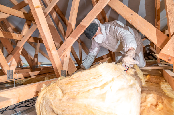 a man insulates the roof and ceiling of the house with glass wool - Foto, Bild