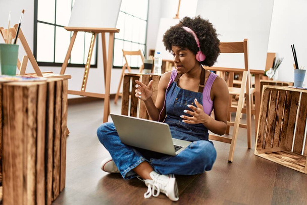 Young african american woman using laptop and headphones at art studio - Photo, Image