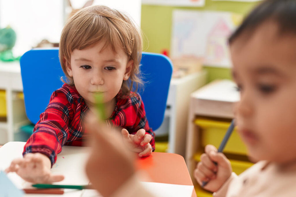 Deux enfants d'âge préscolaire assis sur la table dessinent sur du papier à la maternelle - Photo, image