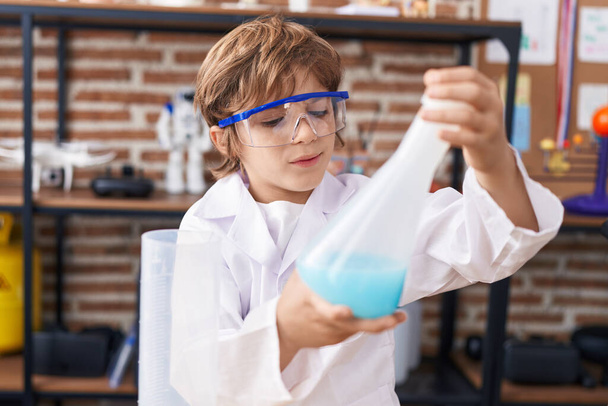 Adorable caucasian boy student holding test tube at classroom - Foto, imagen