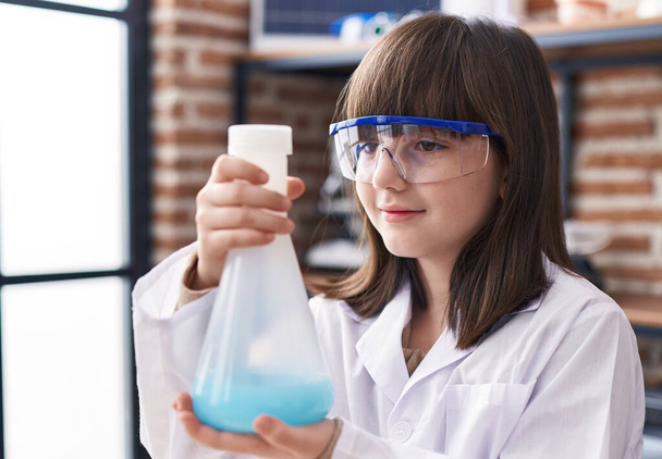 Adorable hispanic girl student holding test tube at laboratory classroom - Foto, afbeelding