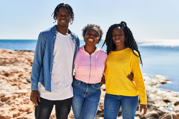 Αφροαμερικανοί φίλοι χαμογελούν με αυτοπεποίθηση αγκαλιασμένοι στην παραλία - Φωτογραφία, εικόνα