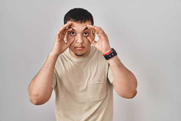 Young arab man wearing casual t shirt trying to open eyes with fingers, sleepy and tired for morning fatigue  - Foto, afbeelding