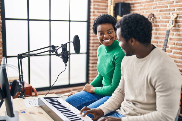 アフリカ系アメリカ人男性と女性の音楽グループの歌は音楽スタジオでキーボードピアノを演奏 - 写真・画像