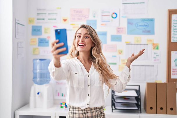 Junge blonde Geschäftsfrau mit Videoanruf im Büro - Foto, Bild