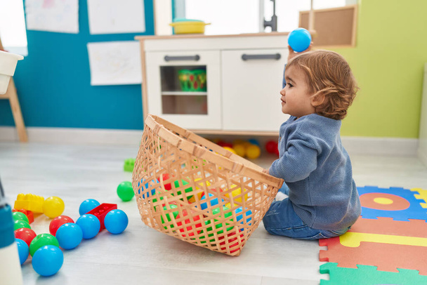 Чарівний іспаномовний малюк грає з кульками, що сидять на підлозі в дитячому саду
 - Фото, зображення