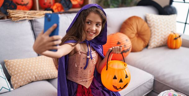 Чарівна іспаномовна дівчина в костюмі Хеллоуїна робить селфі за допомогою смартфона вдома
 - Фото, зображення
