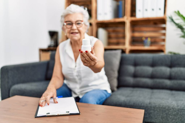 Senior grey-haired woman psychologist prescribing pills at psychology center - Foto, immagini
