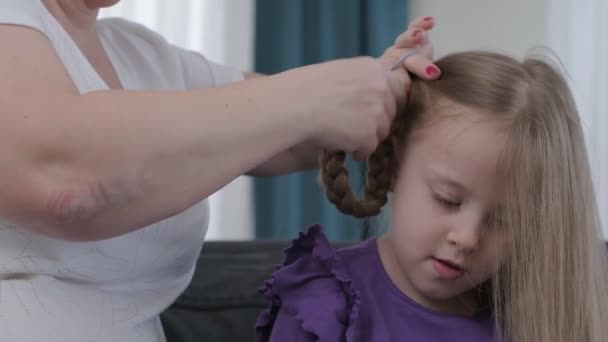 hairdresser brushing child girl blond hair and styling hairdo braid hairstyle getting ready for school or going out - Záběry, video