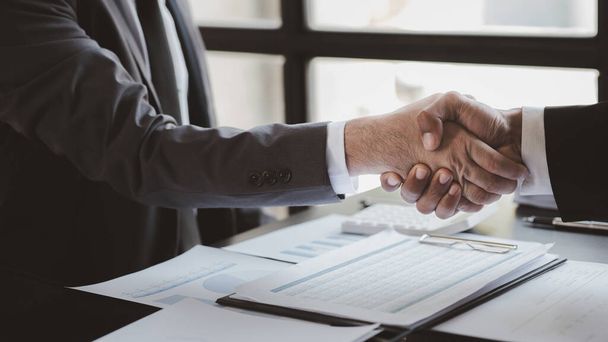 Business investor group holding hands, Two businessmen are agreeing on business together and shaking hands after a successful negotiation. Handshaking is a Western greeting or congratulation. - Fotó, kép