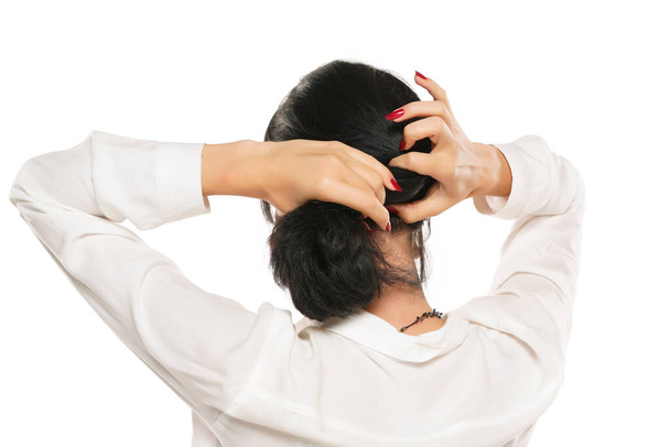woman ties her hair with a barrette on a white studio background - Foto, immagini