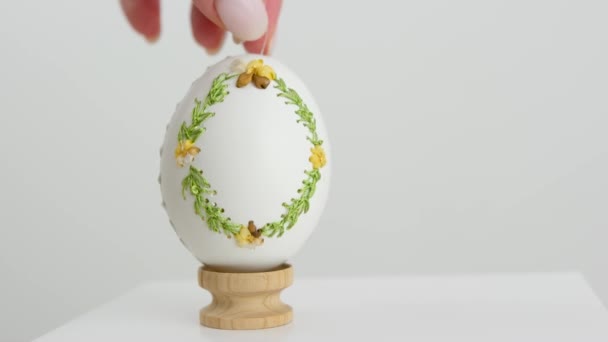 Velikonoční jarní dovolená vaření krashenok zdobit vaječné skořápky výšivky na husí vejce samice ruka dává hotové výrobky na dřevěný stojan bílá manikúra světlo pozadí ruční vejce na Velikonoce - Záběry, video