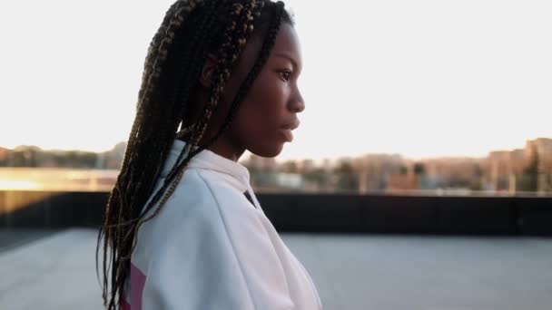 Afrikanische junge Frau mit Dreadlocks, im Profil beim Betrachten der Stadt. - Filmmaterial, Video