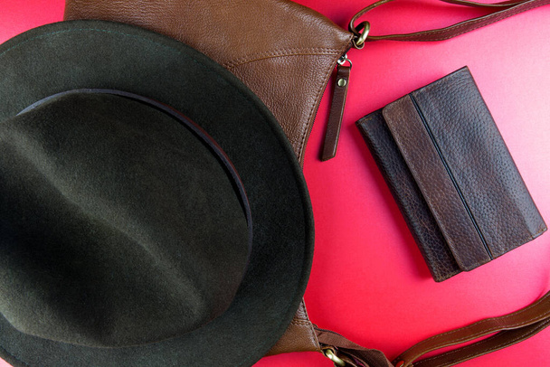 Leather bag with felt hat and leather wallet on a red table top - Foto, Imagen